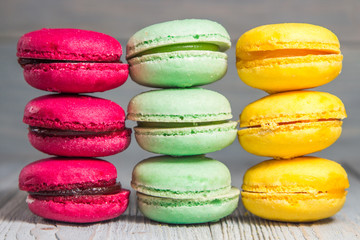 Три стопки разноцветных макарун на деревянном фоне