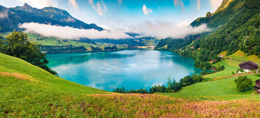 Foggy summer panorama of Lungerersee lake. Colorful morning view of Swiss Alps, Lungern village...