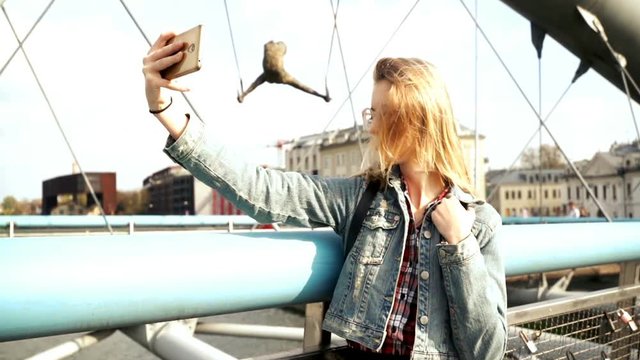 Woman taking photo with cellphone on the bridge in the city.
