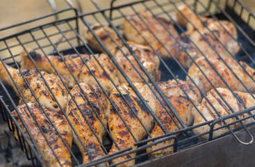 Chicken legs cooking in barbecue on smouldering carbons.