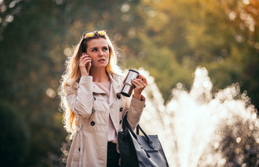 Modern woman in rush walking on street using smartphone outdoor