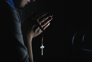 Woman hands holding rosary on black background
