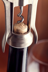 Corkscrew and a glass of wine on an old wooden table
