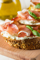 Italian tomato, prosciutto, jamon, ham and cheese bruschetta. Tapas, antipasti with chopped vegetables, herbs and oil on grilled ciabatta and baguette bread.