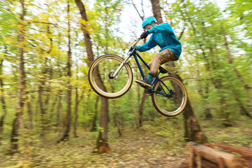 Naklejka premium a young guy in a helmet flies landed on a bicycle after jumping from a kicker