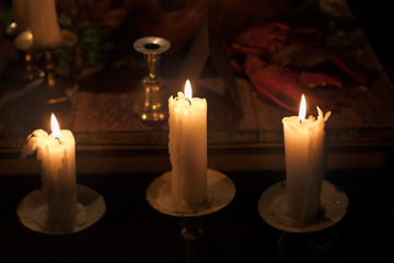 Three candles burning on a wooden food platter table at an event