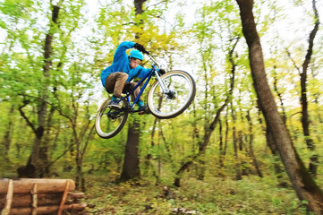 Naklejka premium a young guy in a helmet flies landed on a bicycle after jumping from a kicker