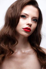 Fototapeta premium A young girl with a Hollywood wave and classic makeup. Beautiful model with red lips and arrows on eyes. Evening makeup and hairstyle. Beauty of the face. White isolated background. Shining skin.
