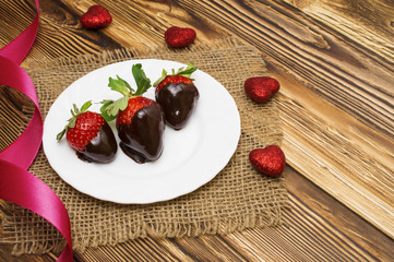 Fresh strawberries dipped in dark chocolate and heart on wooden background. Valentine's Day