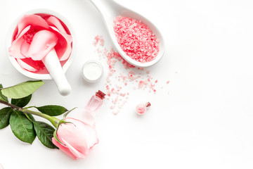 Make cosmetics with rose  oil. Mortar with rose petals and pestle on white background top view copyspace
