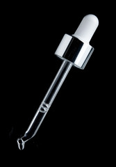 transparent glass pipette with falling drops close-up on black background