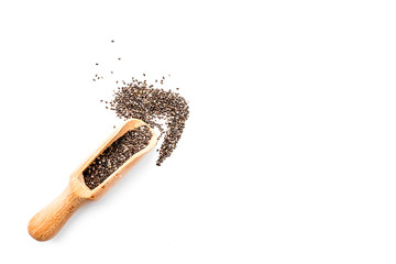 Dark chia seeds in wooden scoop on white background top view copyspace