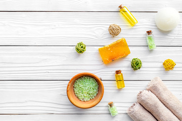Foot spa cosmetics. Spa salt, pumice stone, soap and towel on white wooden background top view copyspace
