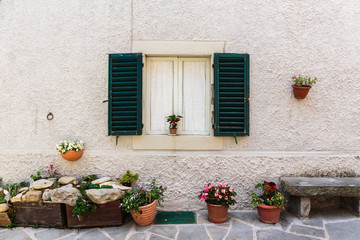 Fototapeta na wymiar Window in an old house decorated with flower pots and flowers