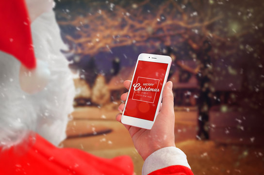 Santa Claus holding smart phone with Merry Christmas massage. Winter and snow outdoor in background.