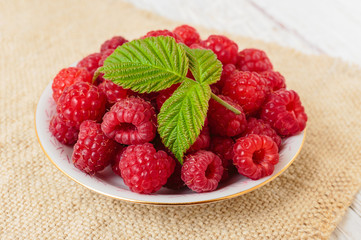 Raspberries in a bowl on a wooden white table
