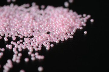 Pink seed beads scattered on a dark surface