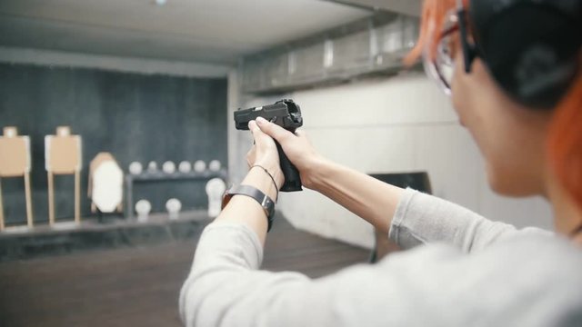 Woman shooting with a gun in shooting gallery, slow-motion