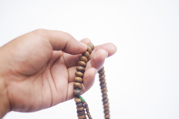 Hand Holding Muslim Rosary Beads Over White Background