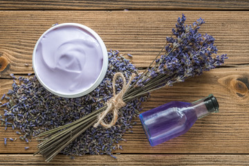Lavender cream or balm, essential oil, mortar of dry lavender and bunch of dried flowers. Top view, flat lay.
