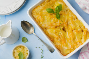 Mac and cheese. Casserole from pasta, cheese and béchamel sauce in ceramic form on light concrete or stone background. Selective focus. Top view. Copy space.