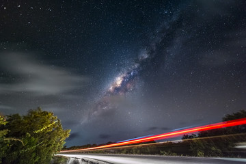 Night sky with milky way and stars. Night road illuminated by car. Light trails Colorful Galaxy