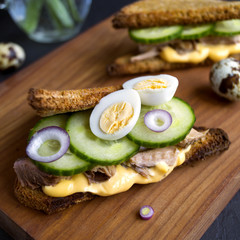 Healthy sandwich with tuna, cucumber and sauce. on a wooden Board. black background