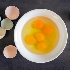 Fresh eggs in a white bowl. Concept of organic products. Farm. Broken eggs with bright yolks.