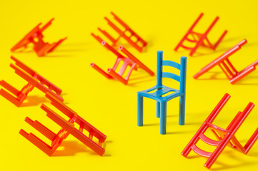 Unique red chair in a group blue others. Leadership concept. Empty chairs  on yellow background. The concept of uniqueness, distinction from others.