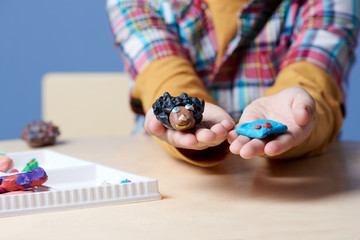 Boy is demonstrating colorful modelling clay crafts. Close up.