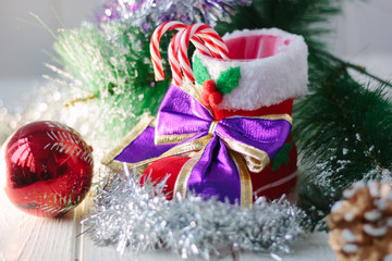 White christmas decoration with the red santa boot and candy canes inside it.