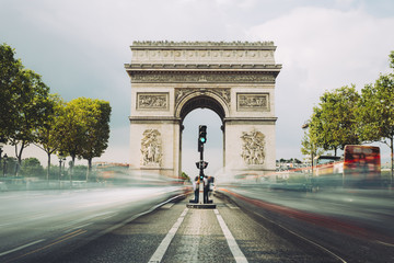 Famous avenue Champs-Elysees and the Triumphal Arch, symbol of the glory and historical heritage. Iconic touristic architectural landmark of Paris, France. Tourism and travel concept. Long exposure.