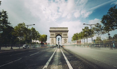Famous avenue Champs-Elysees and the Triumphal Arch, symbol of the glory and historical heritage. Iconic touristic architectural landmark of Paris, France. Tourism and travel concept. Long exposure.