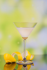 Glasses of cream liqueur with lime and lemon on green background with reflection.