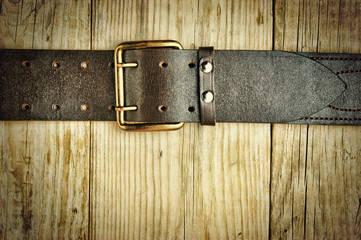 leather belt with a buckle on a wooden board