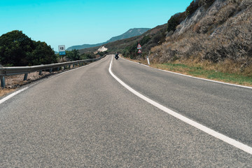 Motorcyclist driving on mountain road in summer. Sardinia. Italy.