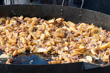 Potatoes with meat on a huge frying pan. Outdoor food. Cafe on the street. Zharkoe.