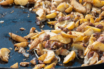 Potatoes with meat on a huge frying pan. Outdoor food. Cafe on the street. Zharkoe.