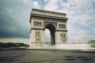 Fototapeta na wymiar Famous Triumphal Arch, symbol of the glory and historical heritage. Iconic architectural landmark of Paris, France. Charles de Gaulle square. City traffic, tourism and travel concept. Long exposure.