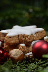 Cinnamon stars with hazelnuts and red Christmas balls on fir sprigs