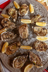 Oysters with lemon and ice on the plate on the dinner table