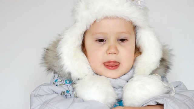 A funny happy child dressed in warm fur clothes looks at the camera, laughs and smiles. Close-up portrait. The concept of winter, frost and snow, cold weather, Cool temperature and Christmas