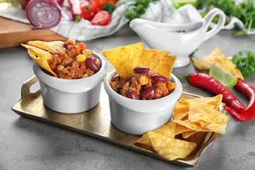 Chili con carne in bowls served with chips on kitchen table