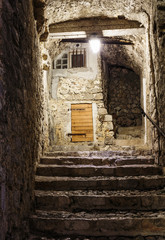 Narrow cobbled street in old town Peille at night, France.