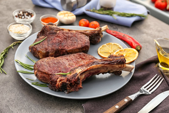 Plate with yummy grilled steaks on kitchen table