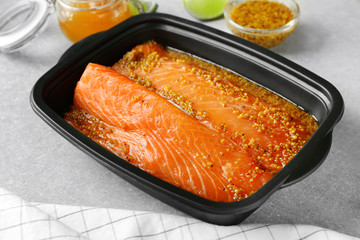 Dish with salmon fillet in honey mustard marinade on table
