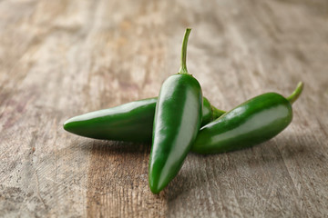 Green jalapeno peppers on wooden background