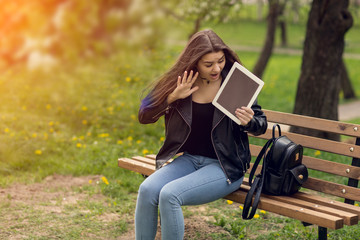 Young girl in the park with a tablet in hand.
