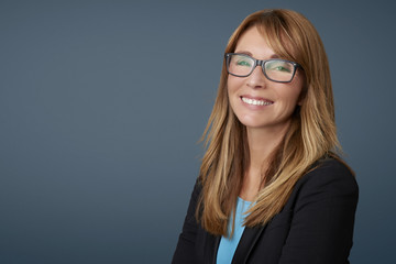 Attractive middle aged businesswoman against grey background.