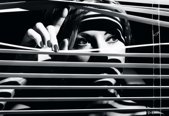 Closeup shot of sexy young woman looks through the jalousie